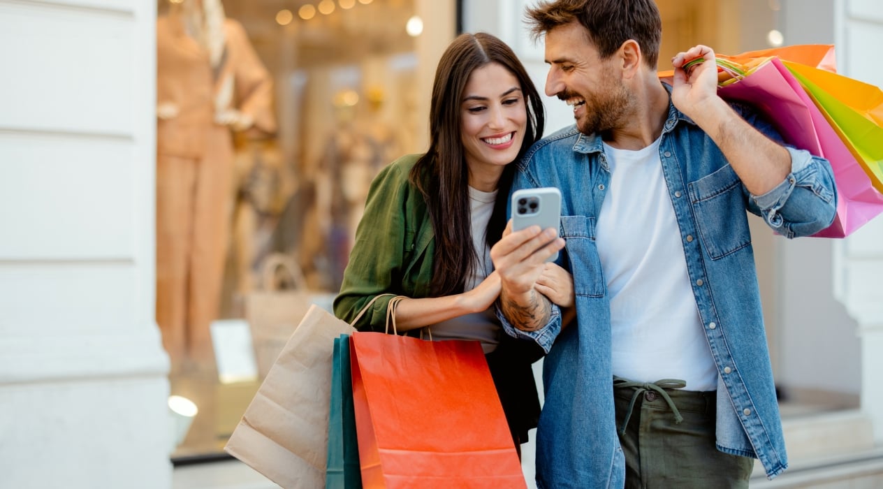 Young Happy Couple With Smart Phone and Shopping Bags